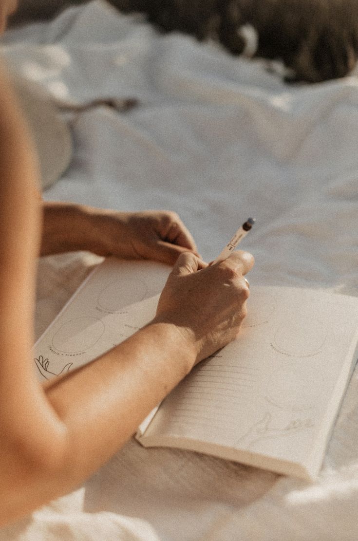 Hands writing thoughtfully in a journal with warm natural lighting, capturing the peaceful practice of reflective writing